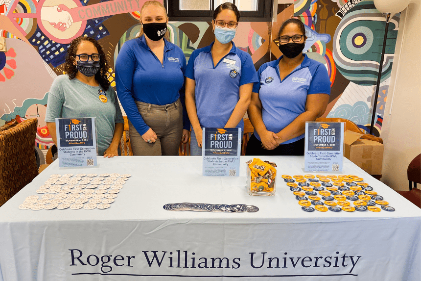 Students stand behind table with buttons and stickers