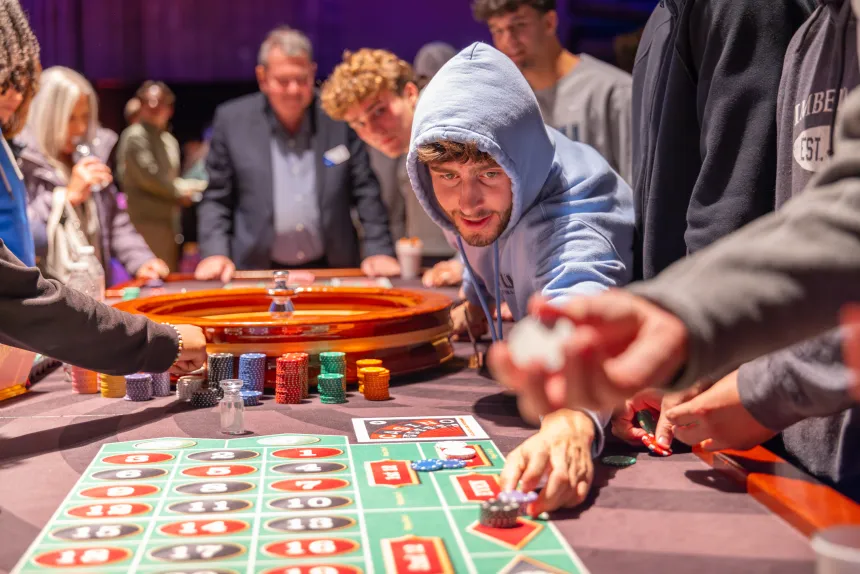 A student confidently slides his chips along the roulette board.