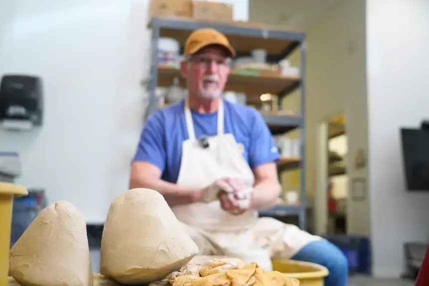 Denis Leonti molds clay as he sits behind the wheel.