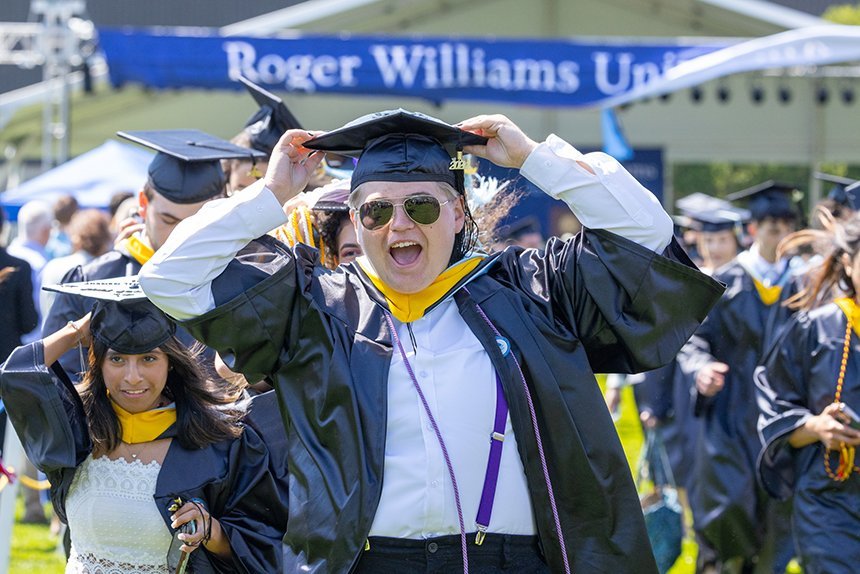 Graduates cheer and hold onto hats