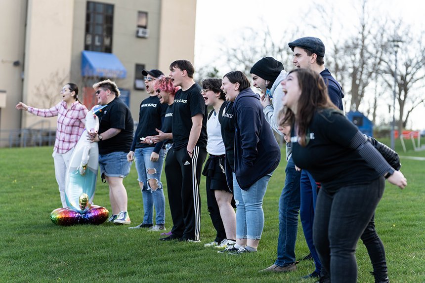 Students on the lawn outside GHH stand in a line and scream. 