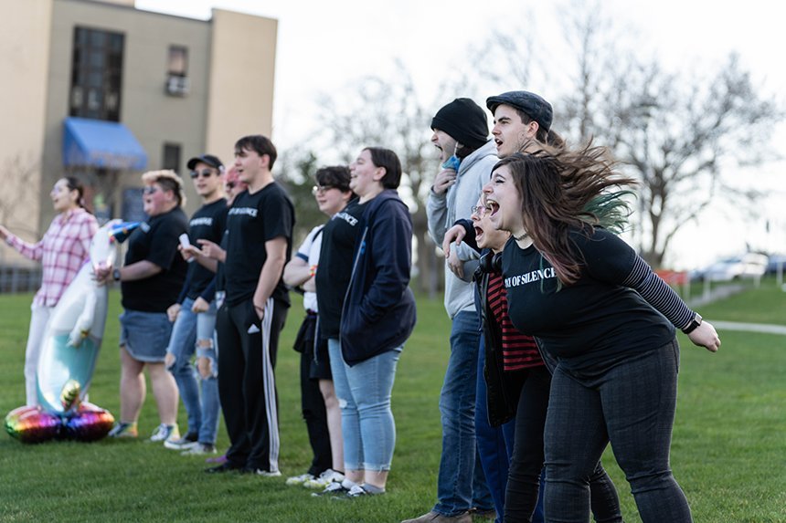 Students on the lawn outside GHH stand in a line and scream. 