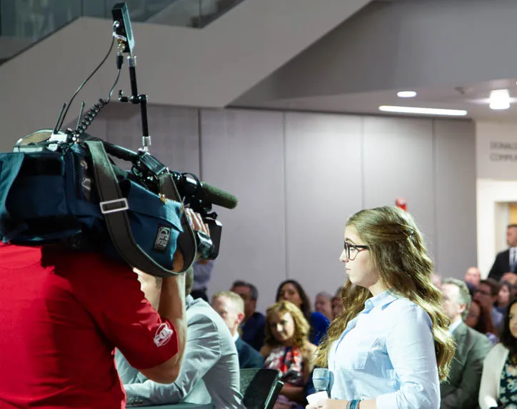 Side profile of student with film crew. 