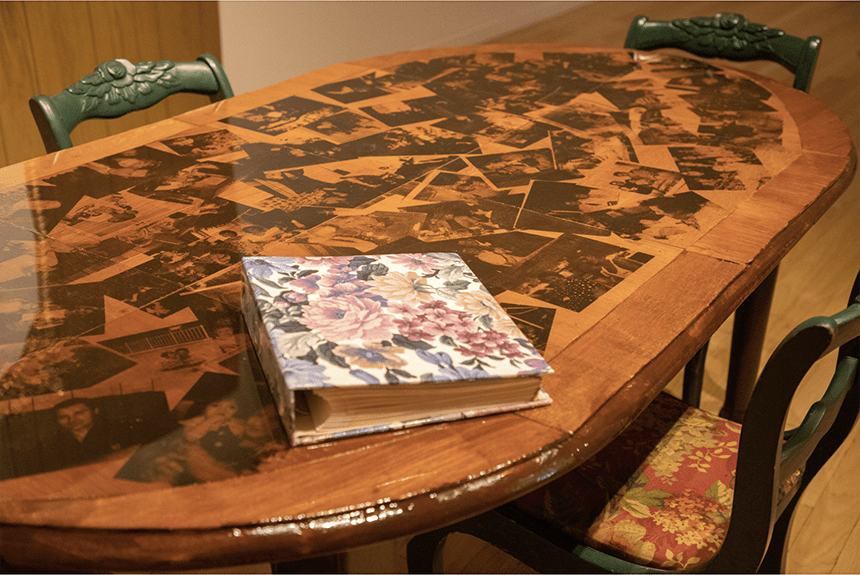 Repurposed Kitchen Table with Screen-printed Archive Family Photographs. Sealed with Resin. Displayed with gathered family artifact seating.