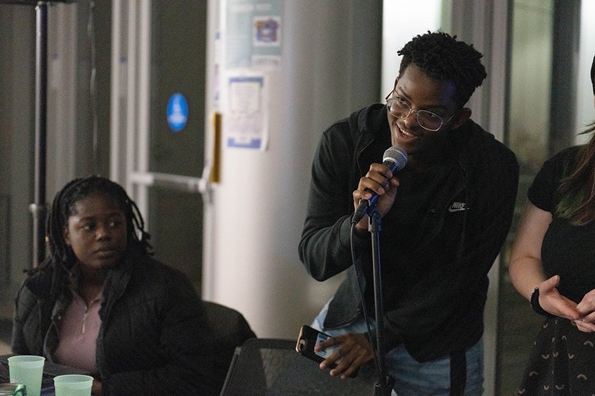 Two MSU officers, one speaking into a microphone and one sitting. 