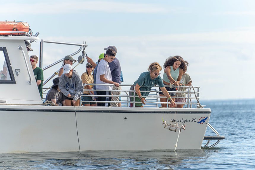 Students lowering a water collection device into the Mount Hope Bay. 