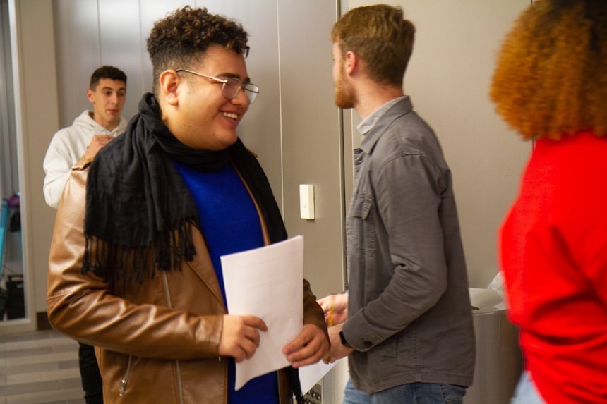 Student smiles, holding paper.