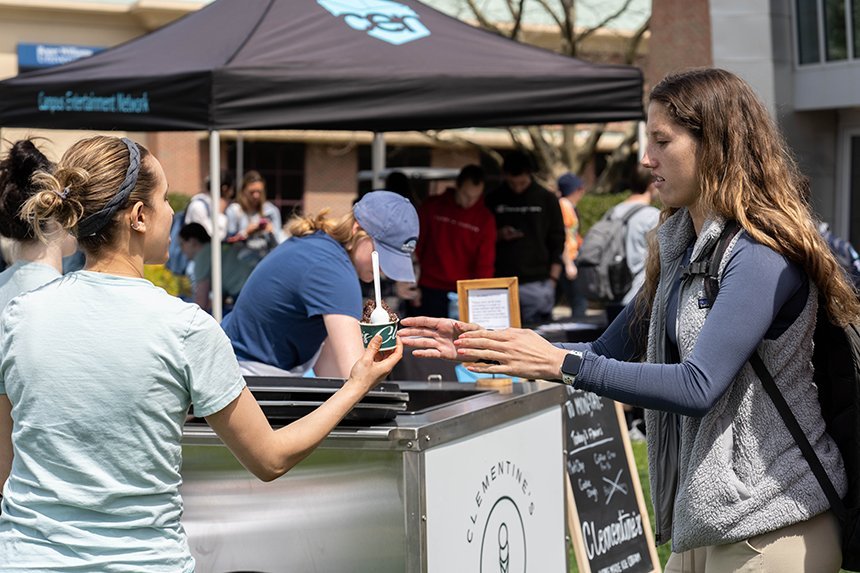 A Clementine's staff member hands a student a cup of ice cream. 