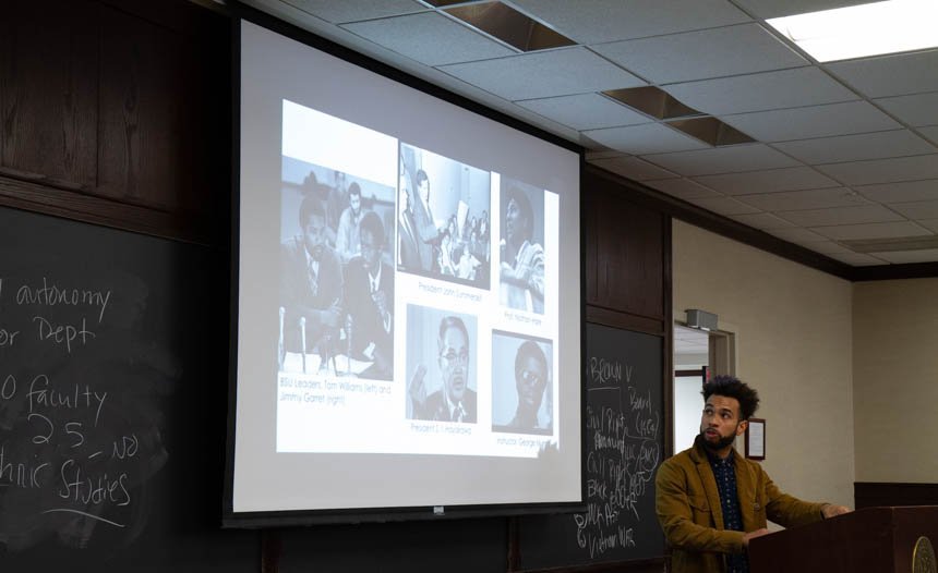 Professor looks at projector screen with images.