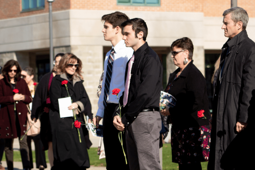 Guests prepare to lay carnations at the base of the flag.