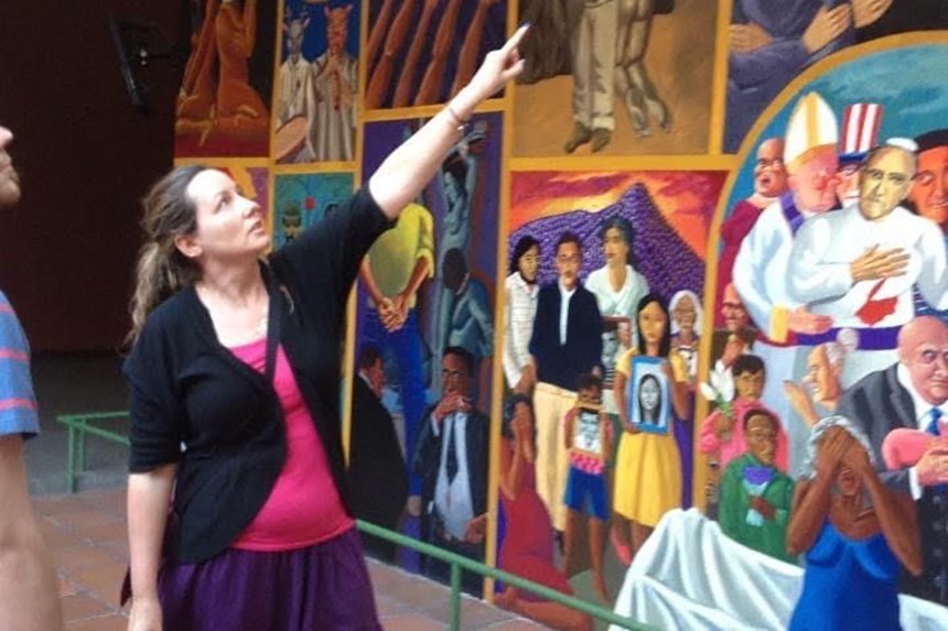 Autumn Quezada-Grant points at a mural