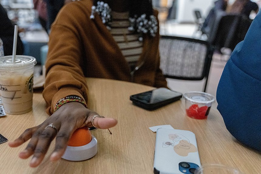 A student pressing an orange buzzer during a game of Jeopardy. 