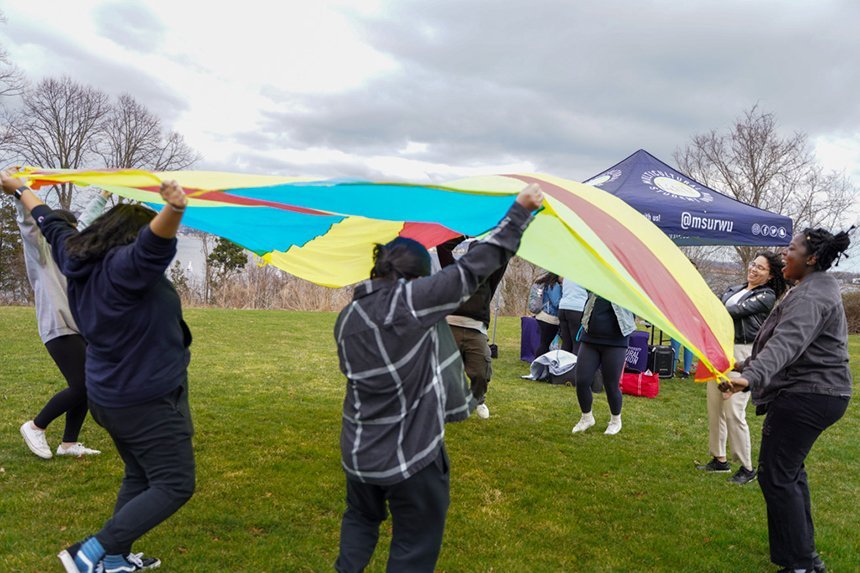 Students at MSU's Field Day event toss up a playground parachute. 