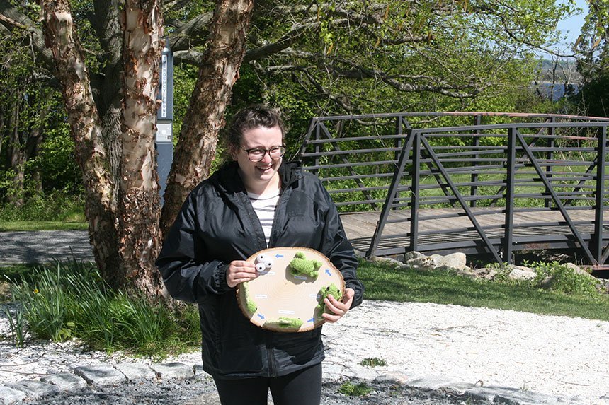 Student displays her crocheted work of a frog's life cycle.